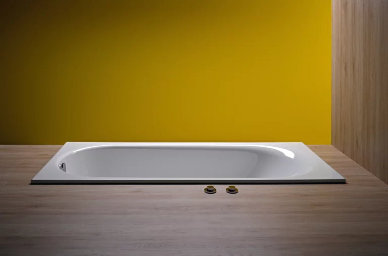 Rectangular steel enamel bathtub, flat inset into wood-look floor, in front of yellow wall.