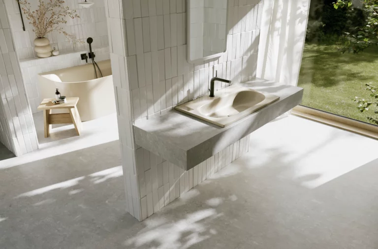 Helles Badezimmer mit beigem Waschtisch, schwarzen Armaturen und großer Fensterfront mit Blick in den grünen Garten.
