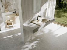 Helles Badezimmer mit beigem Waschtisch, schwarzen Armaturen und großer Fensterfront mit Blick in den grünen Garten.