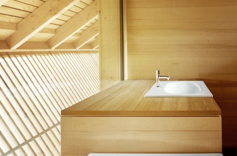 Quadratisches Stahl-Email Waschbecken auf rechteckiger Einbauplatte aus Holz, minimalistisch in hellem Badezimmer mit viel Tageslicht.