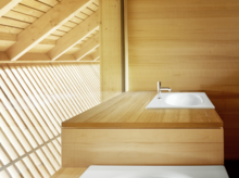 Quadratisches Stahl-Email Waschbecken auf rechteckiger Einbauplatte aus Holz, minimalistisch in hellem Badezimmer mit viel Tageslicht.