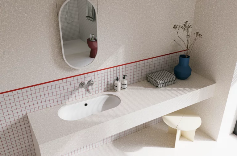 Helles Badezimmer mit weißem Waschtisch, ovalem Spiegel, gefliester Ablage und roter Akzentlinie an der Wand.