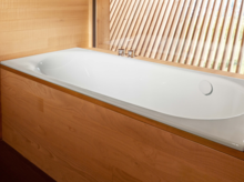 Rechteckige Badewanne aus Stahl-Email, weiß, in eine Holzverkleidung eingebaut, mit Armatur am Rand.