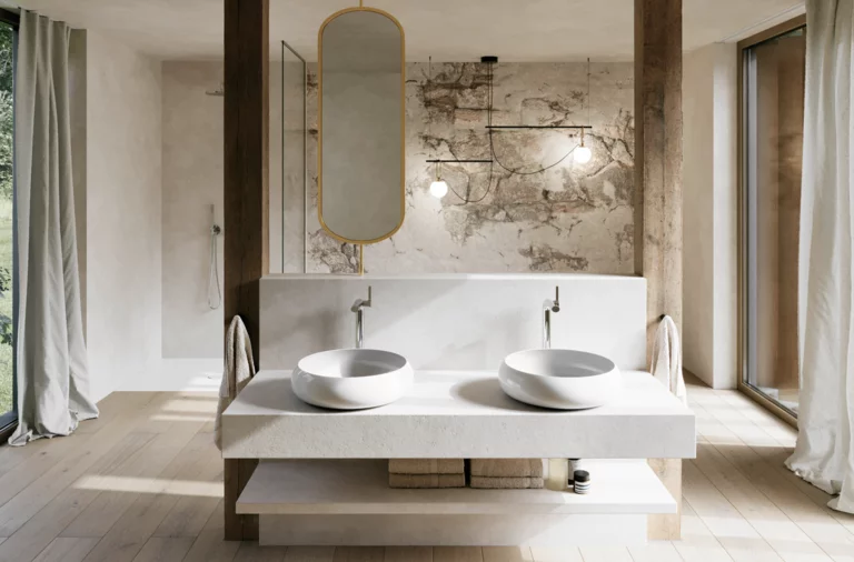 Modernes Badezimmer mit zwei weißen Waschtischen auf breiter Konsole, ovalem Spiegel und markanter Wand in Natursteinoptik.