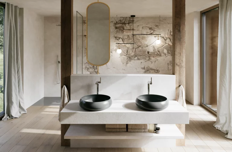 Modernes Badezimmer mit zwei schwarzen Waschtischen auf breiter weißer Konsole, ovalem Spiegel und Wand in Natursteinoptik.