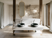 Modernes Badezimmer mit zwei schwarzen Waschtischen auf breiter weißer Konsole, ovalem Spiegel und Wand in Natursteinoptik.