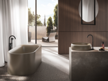 Vrijstaand ovaal bad en ronde wastafel van staal-email op rechthoekig inbouwelement in moderne badkamer.