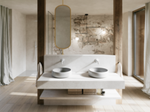 Modernes Badezimmer mit zwei hellgrauen Waschtischen auf breiter Konsole, ovalem Spiegel und markanter Wand in Natursteinoptik.