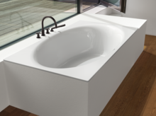 Rectangular steel enamel bathtub with oval interior, built into white paneling, fittings mounted on the side.