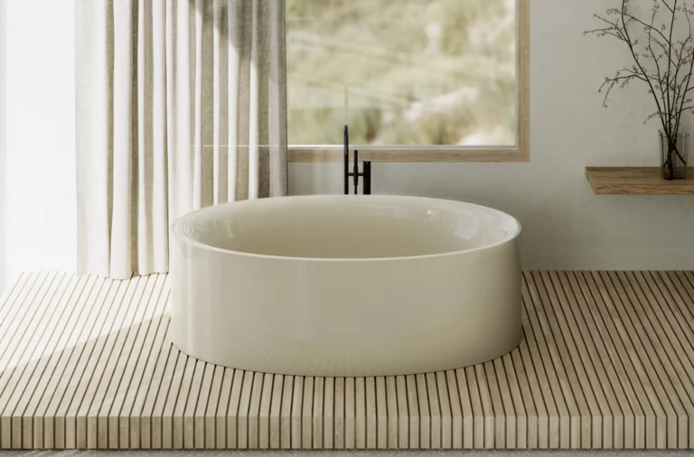 Freestanding oval bathtub in light beige on wooden platform, in front of window with curtain and minimal decor.