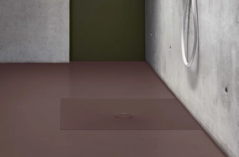 Plato de ducha rectangular de acero esmaltado, a ras de suelo, color mate, con desagüe central en baño moderno.