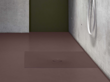 Plato de ducha rectangular de acero esmaltado, a ras de suelo, color mate, con desagüe central en baño moderno.