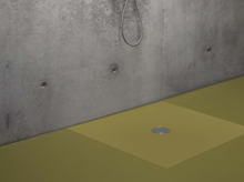 Rechteckige Duschwanne aus Stahl-Email in Beige mit mittigem Abfluss, ebenerdig vor Betonwand installiert.