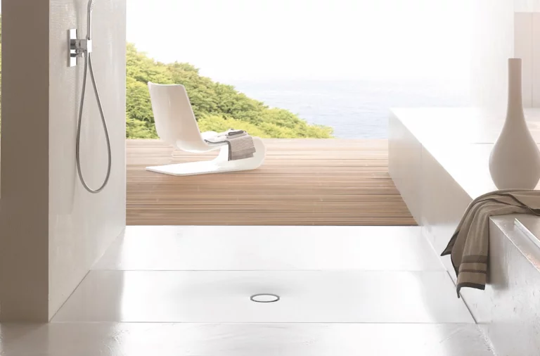 Zona de ducha accesible con plato rectangular de acero vitrificado, diseño minimalista y vista a la terraza y la naturaleza.