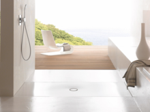 Zona de ducha accesible con plato rectangular de acero vitrificado, diseño minimalista y vista a la terraza y la naturaleza.