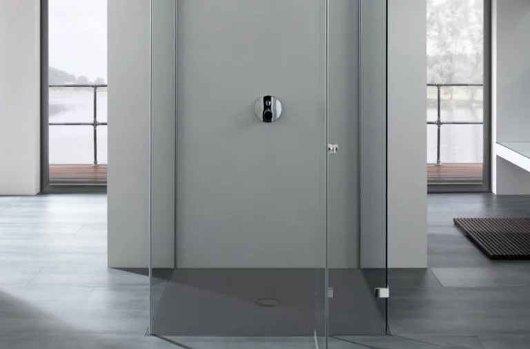 Plato de ducha rectangular de acero vitrificado a nivel del suelo, rodeado de paredes de vidrio, diseño moderno de baño.