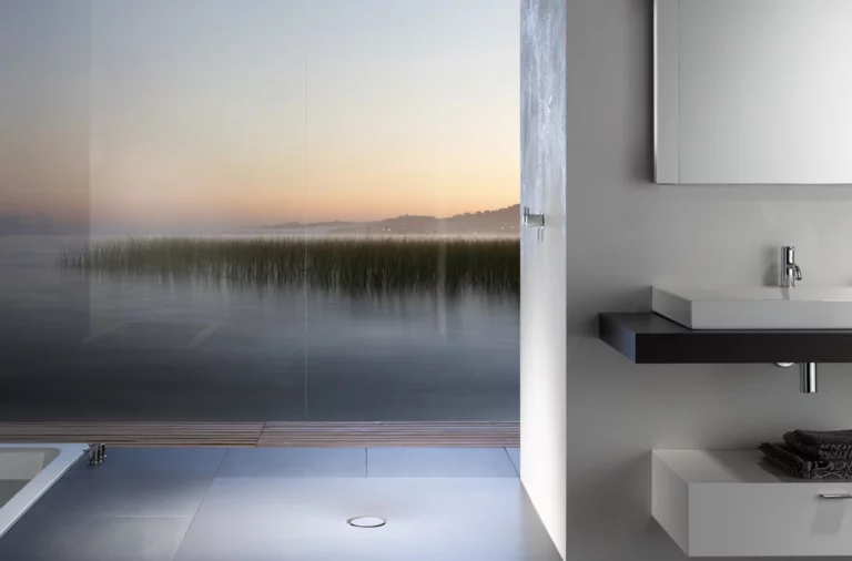 Plato de ducha rectangular de acero esmaltado junto a lavabo rectangular sobre encimera en baño moderno.