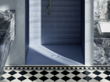 Zona de ducha con plato azul claro, azulejos de pared azules estriados y suelo con baldosas en blanco y negro.