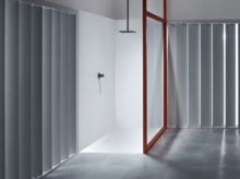 Безбарьерная душевая зона с прямоугольным стальным эмалированным поддоном, вровень с полом, с душевой арматурой и ламелями в качестве экрана.