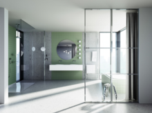 Современная ванная с зелёной плиткой в душе, двойной раковиной, круглым зеркалом и естественным освещением.