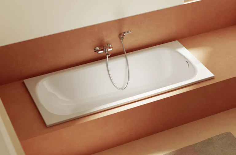 Eingelassene, weiße Badewanne in Verkleidung in warmem Terrakotta-Ton mit Wandarmatur und Handbrause.