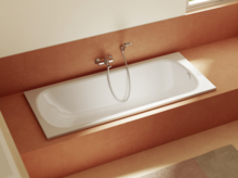Eingelassene, weiße Badewanne in Verkleidung in warmem Terrakotta-Ton mit Wandarmatur und Handbrause.