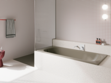 Bañera gris beige de acero titanio esmaltado en baño luminoso con azulejos blancos y ducha abierta.