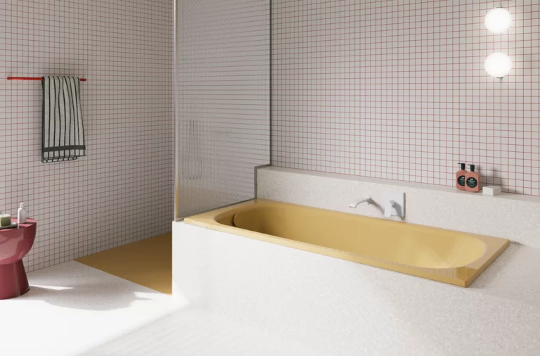 Bañera amarilla de acero titanio esmaltado en baño luminoso con azulejos blancos, grifo mural y ducha abierta.