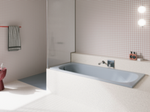 Bañera azul claro de acero titanio esmaltado en baño luminoso con azulejos blancos y ducha abierta.