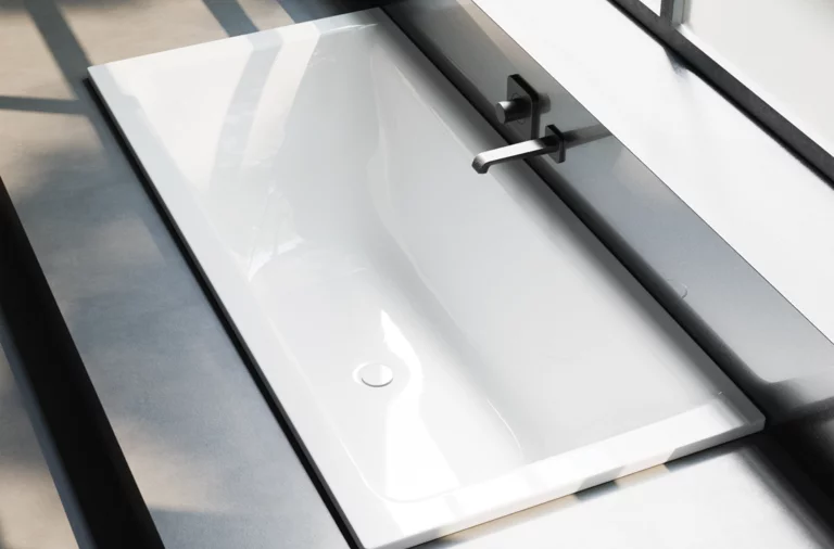 Rechthoekig bad van staal-email, wit, ingebouwd, met wandkraan en overloop, moderne minimalistische uitstraling.