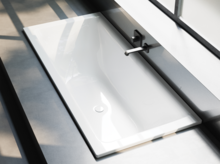 Rechteckige Badewanne aus Stahl-Email, weiß, eingebaut, mit Wandarmatur und Überlauf, moderne minimalistische Optik.