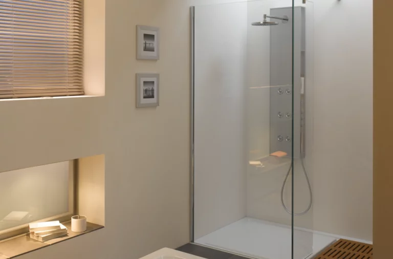 Rechteckige Badewanne und Duschfläche aus Stahl-Email in modernem Bad mit Glasduschwand und Ablage.