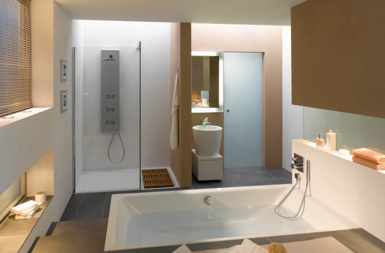 Rechthoekig bad en douchebak van staal-email, apart rond wastafel, modern, licht badkamer met strakke lijnen.