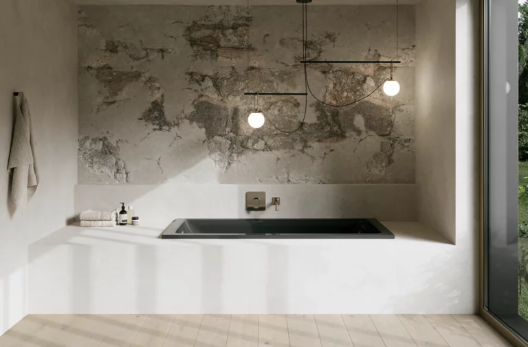 Minimalistisches Bad mit eingelassener Badewanne, grauer Steinwand, Pendelleuchten und großem Fenster.