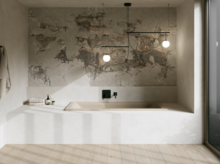 Minimalistisches Bad mit eingelassener beiger Badewanne, grauer Strukturwand, Pendelleuchten und großem Fenster.