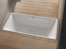 Rechteckige Badewanne aus Stahl-Email, in Holzfläche eingelassen, mit klaren Kanten und mittig angeordnetem Ablauf.