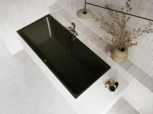 Schwarze Badewanne in hellem Bad mit weißen Fliesen, Armatur, Handtuch und Vase mit Zweigen.