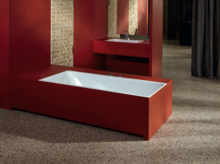 Rechteckige Badewanne aus Stahl-Email und rechteckiges Waschbecken auf Einbauplatte, beides mit roter Verkleidung.