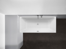 Rechteckige Badewanne aus Stahl-Email mit Ab- und Überlauf, eingebaut in dunklem Boden und heller Wand.