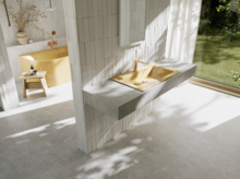 Bright bathroom with a yellow washbasin and faucet in front of a large window overlooking the green garden.