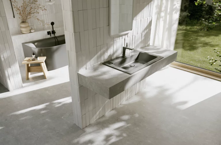 Bright bathroom with a dark grey washbasin and black faucet in front of a large window overlooking the green garden.