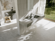 Bright bathroom with a dark grey washbasin and black faucet in front of a large window overlooking the green garden.
