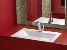 Rechteckiges Stahl-Email-Waschbecken in weiß, flächenbündig in rote Einbauplatte integriert, moderner Wasserhahn, großer Spiegel.