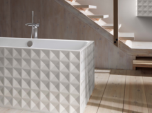 Vrijstaande, rechthoekige badkuip van staal-email met geometrisch gestructureerde buitenzijden op lichte houten vloer.