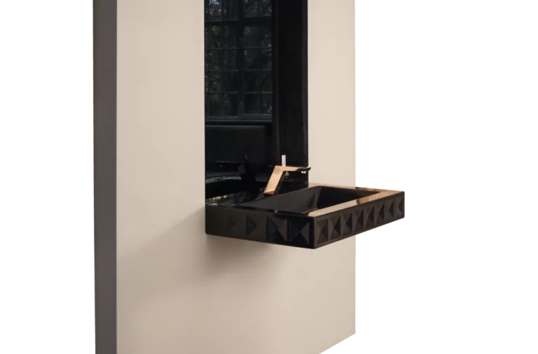 Современная прямоугольная раковина из стальной эмали на черной столешнице перед грубой стеной, большой зеркало сзади.