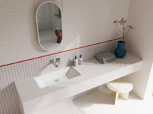 Bright bathroom with a white washbasin, oval mirror, tiled counter and a red accent line along the wall.