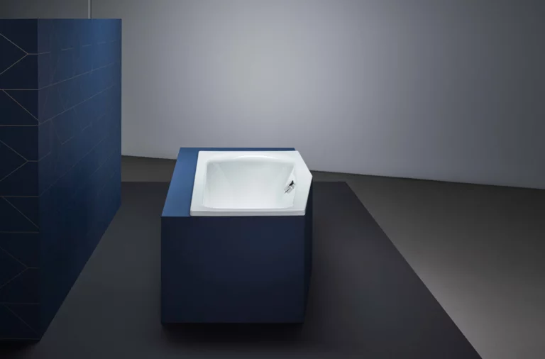 Rechteckige Badewanne aus Stahl-Email, in blauer Verkleidung, freistehend in modernem, minimalistischem Badezimmer.