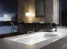 Baignoire rectangulaire en acier émaillé, lavabo rectangulaire sur plan noir, salle de bain luxueuse avec mur en marbre.