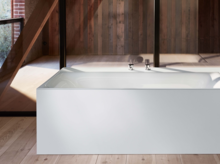 Baignoire rectangulaire en acier émaillé, blanche, autoportante dans pièce moderne avec éléments en bois et en verre.