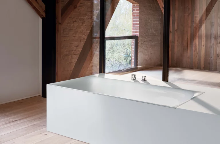 Rechteckige Stahl-Email-Badewanne, freistehend, mit klaren Kanten in einem hellen, modernen Raum mit Holzelementen.